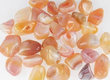 photo of banded tumbled carnelian from namibia, similar to botswana agate but peach, yellow, and pinks with white